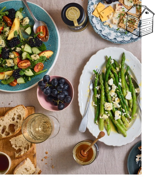 Table setting with various dishes including a salad, asparagus, and bread.
