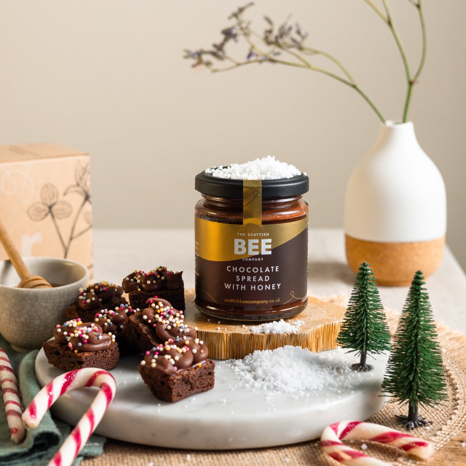 Jar of chocolate spread with honey on a table with cookies and decorative elements