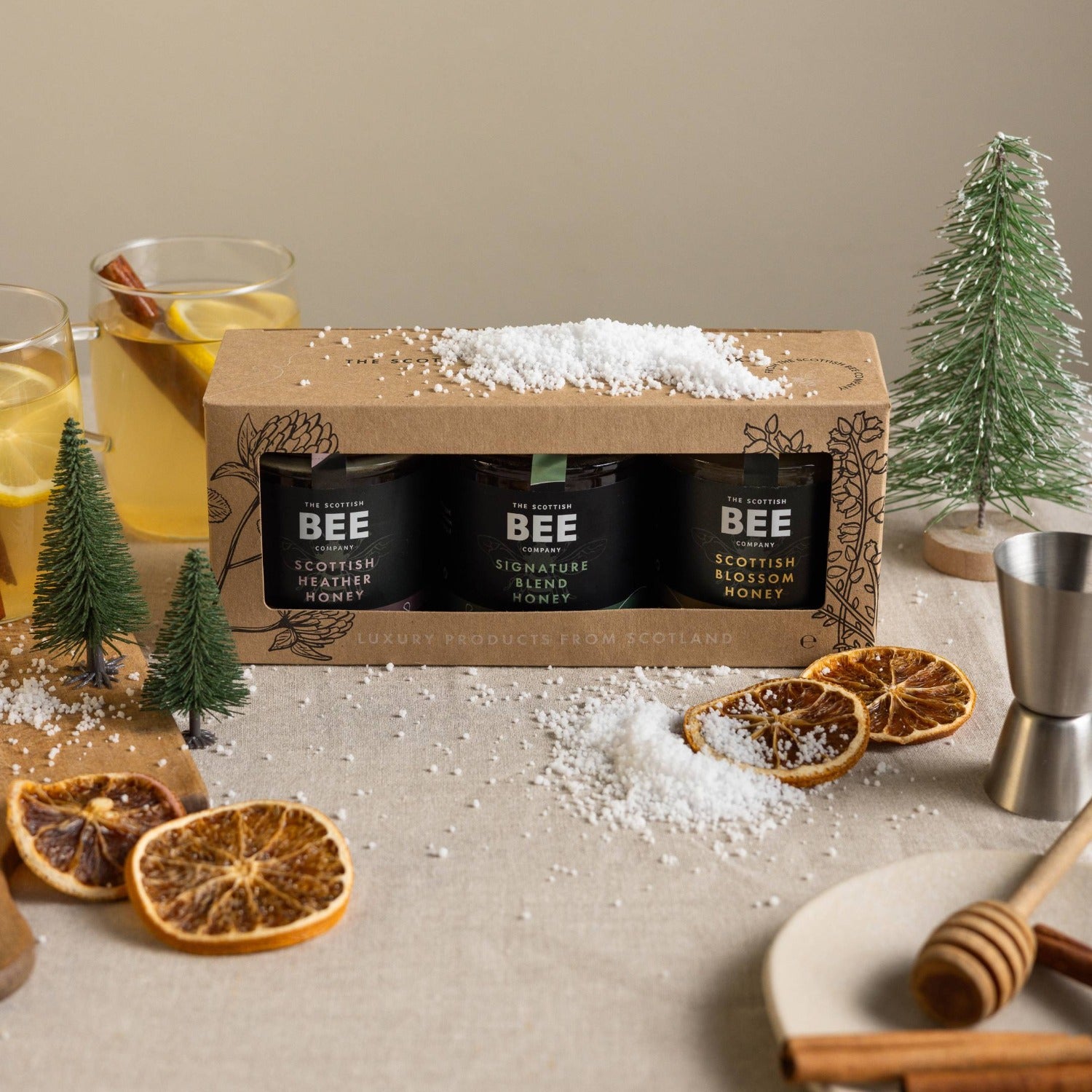 Box of BEE Scottish Heather Honey with honey dipper and oranges on a table