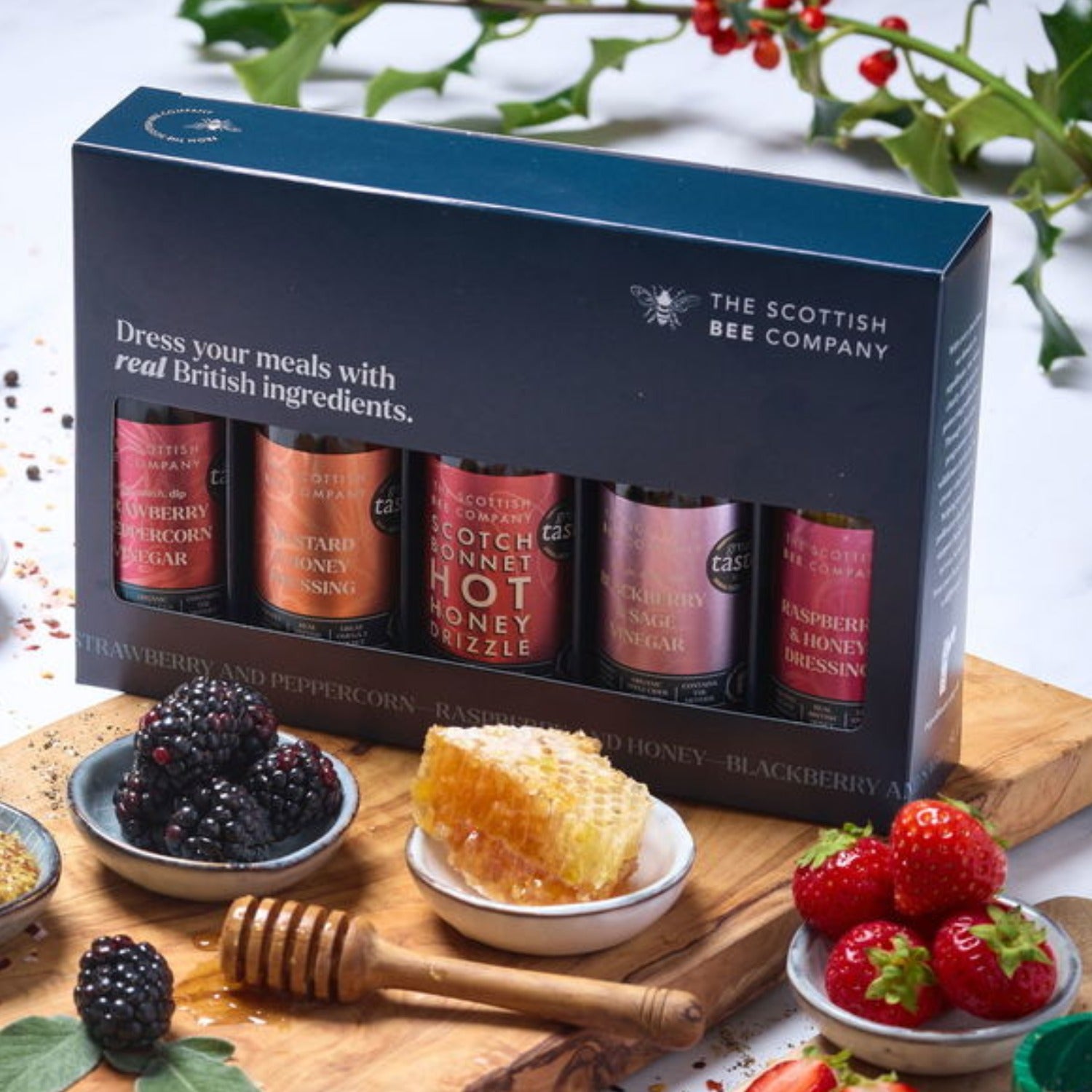 Honey product set from The Scottish Bee Company on a wooden board with honeycomb and berries.
