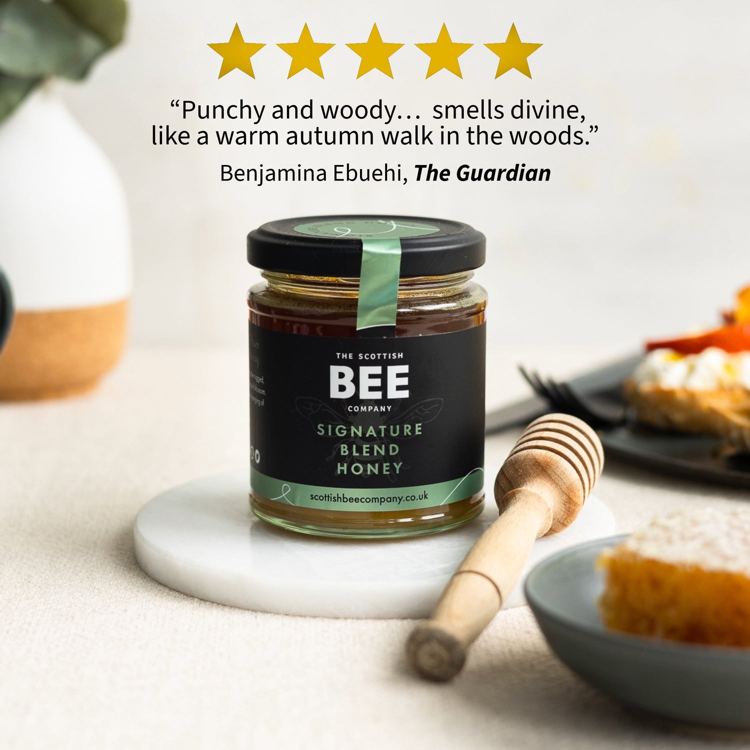 Jar of honey with a honey dipper on a table, featuring a five-star rating and review text.