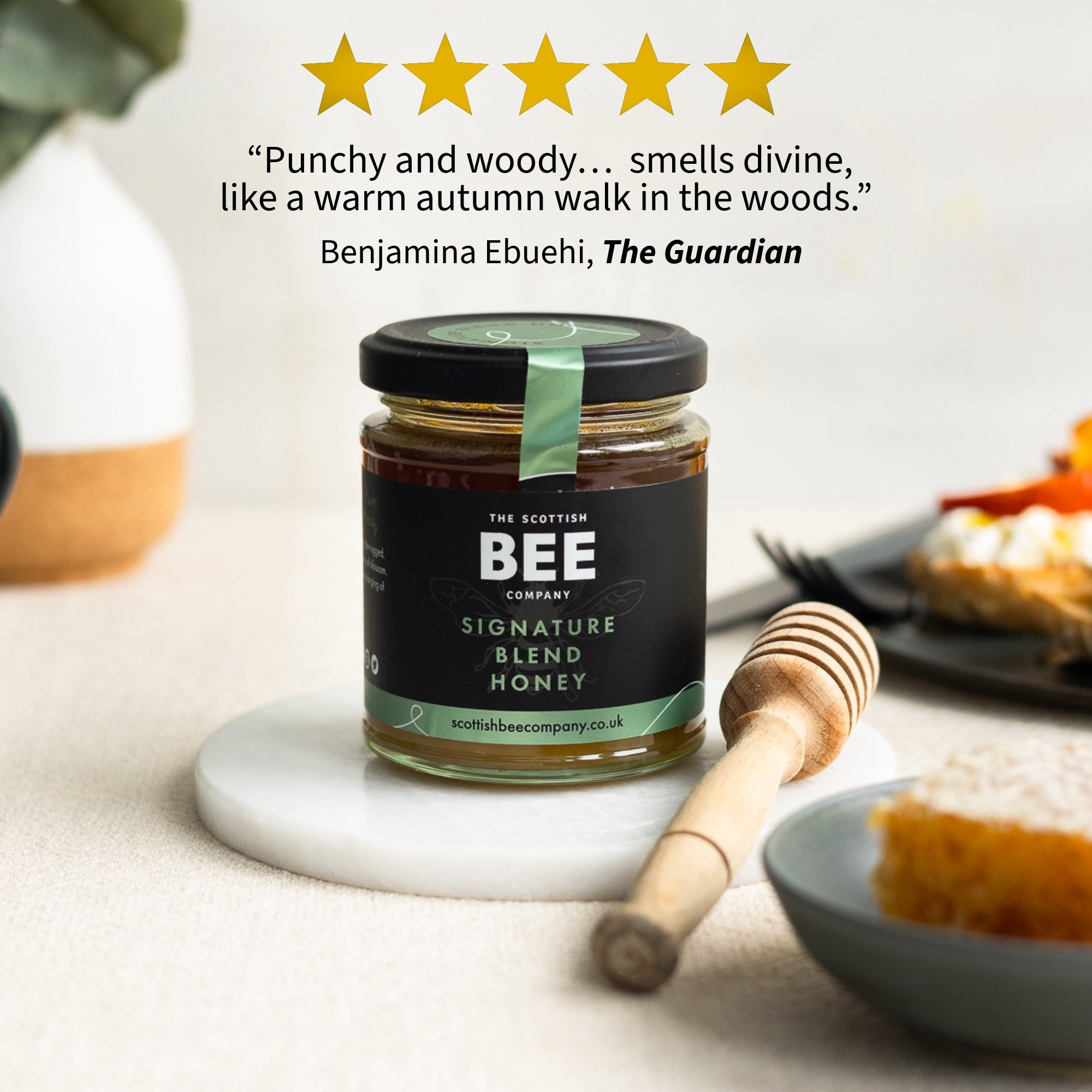 Jar of honey with a honey dipper on a table, featuring a five-star rating and review text.