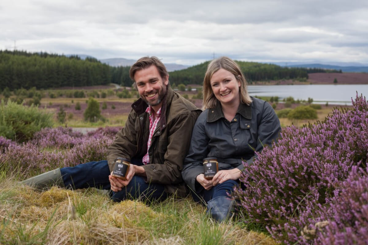 Suzie and Iain in the heather hills with jars of heather honey