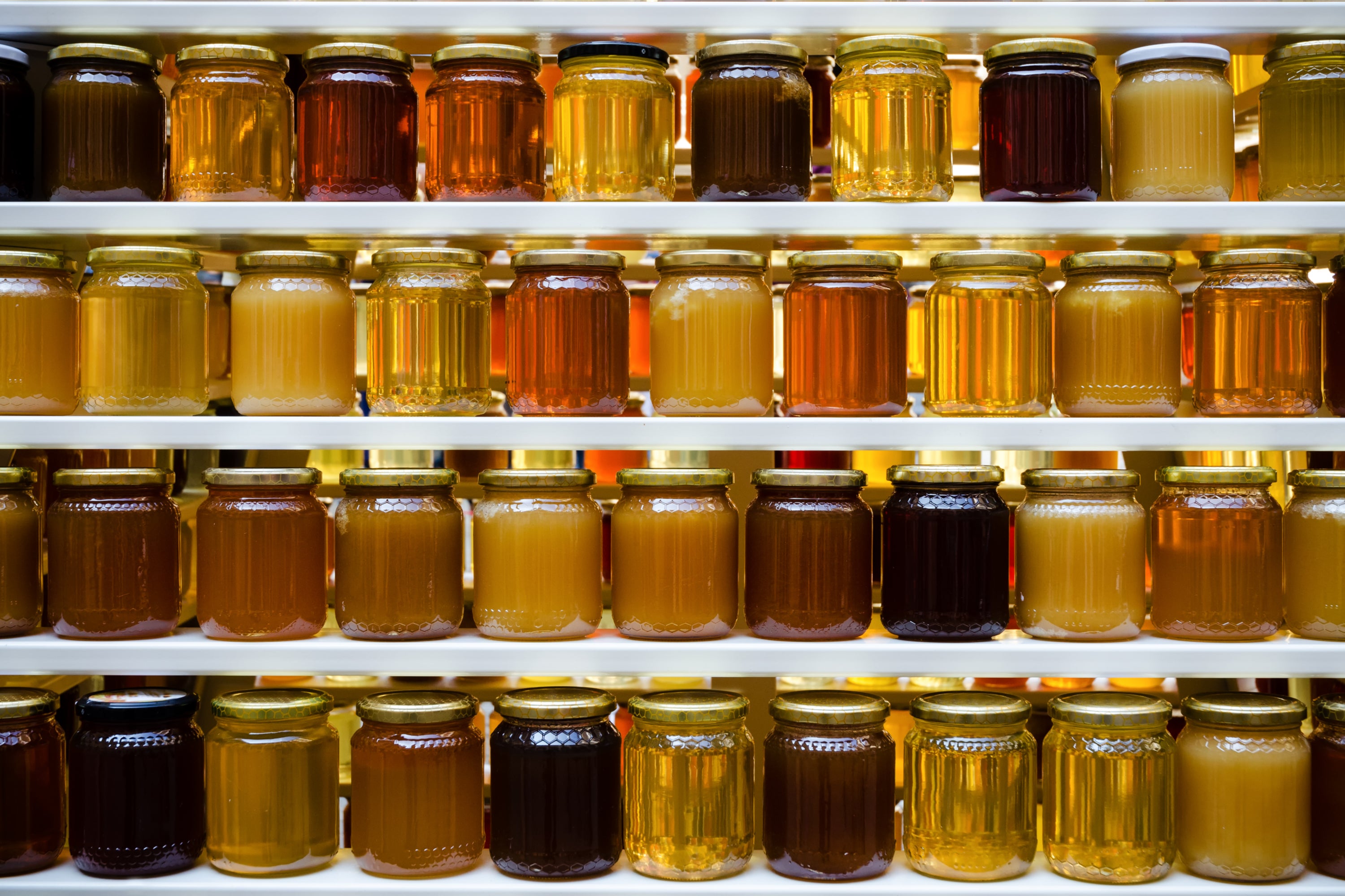 Jars of crystallised and runny honey on shelves