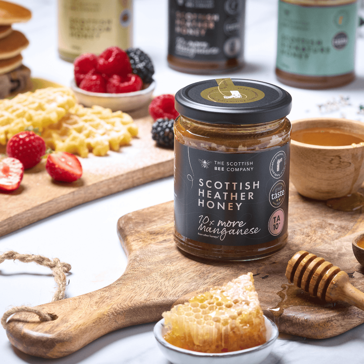 Jar of Scottish Heather Honey with honeycomb and berries on a wooden board