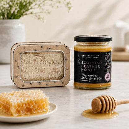 Jar of Scottish Heather Honey with honeycomb and dipper on a table