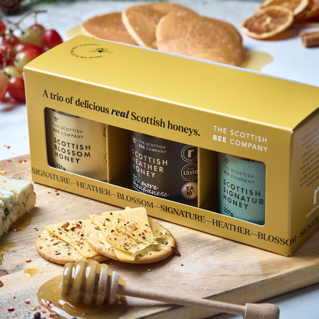 Box of Scottish honey with honeycomb and dipper on a wooden board