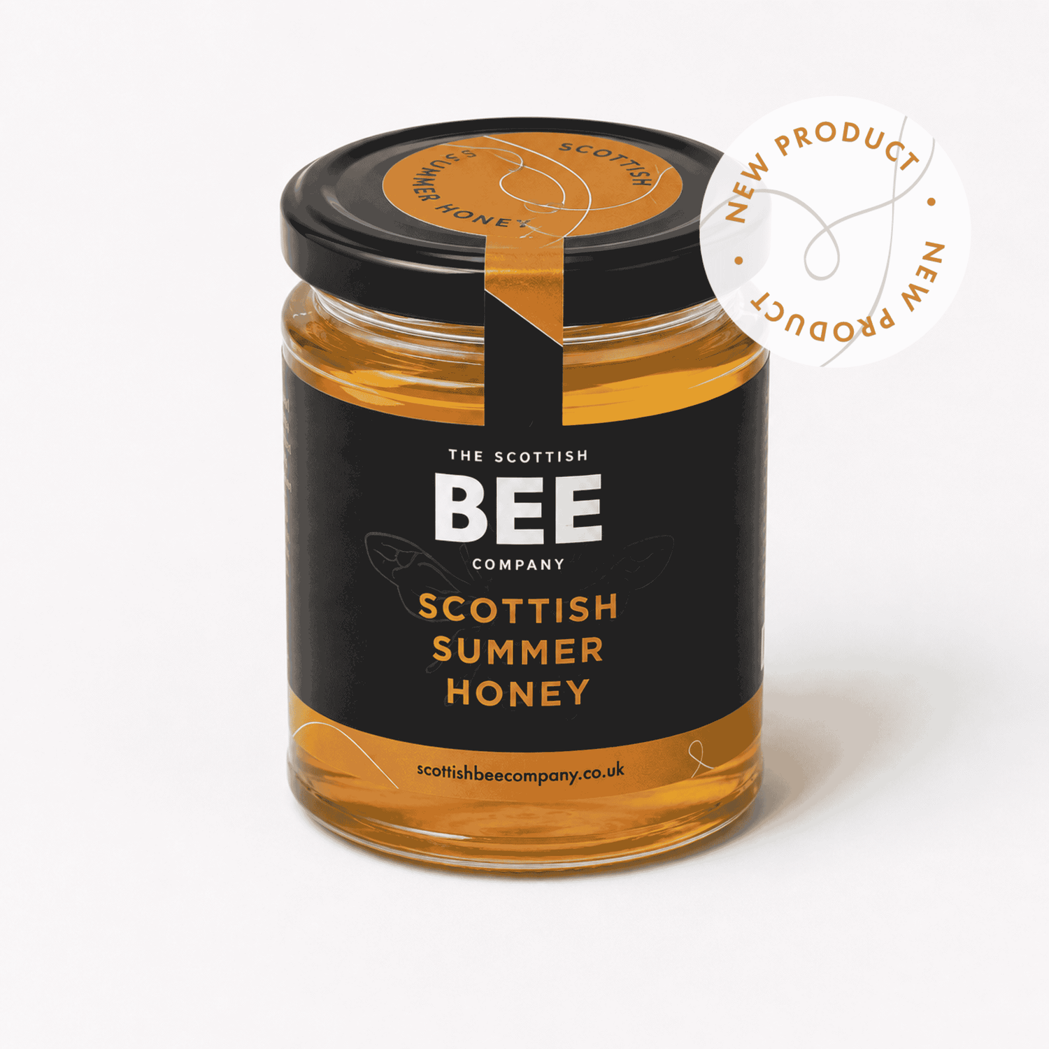 A glass jar of Scottish Summer Honey from The Scottish Bee Company, featuring a black label with gold and white text, a black lid with a gold seal, and a white circular &