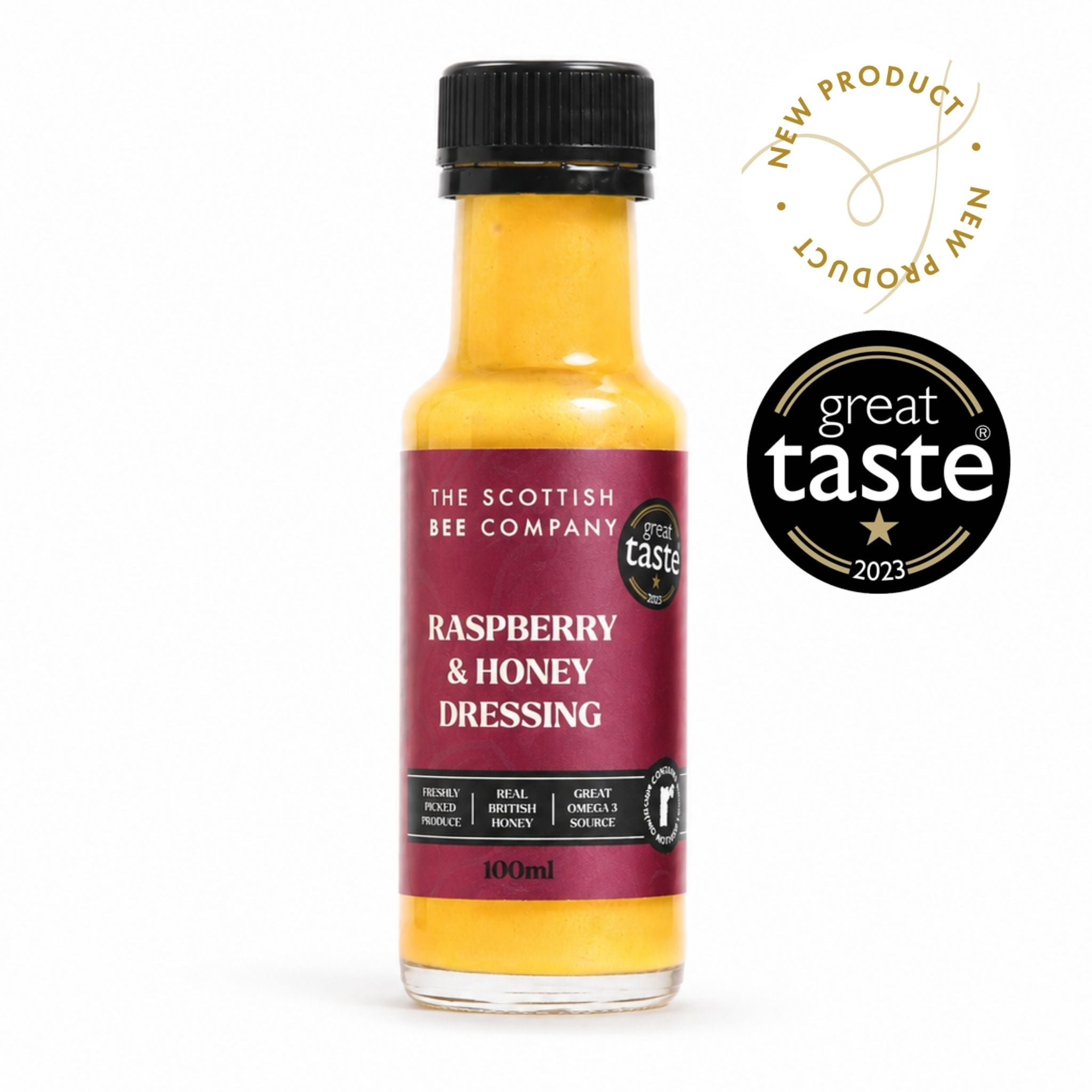 A 100ml bottle of The Scottish Bee Company Raspberry &amp; Honey Dressing, showing the yellow-orange liquid inside, a dark red label, and a black cap. Two badges are displayed on the right: a gold &