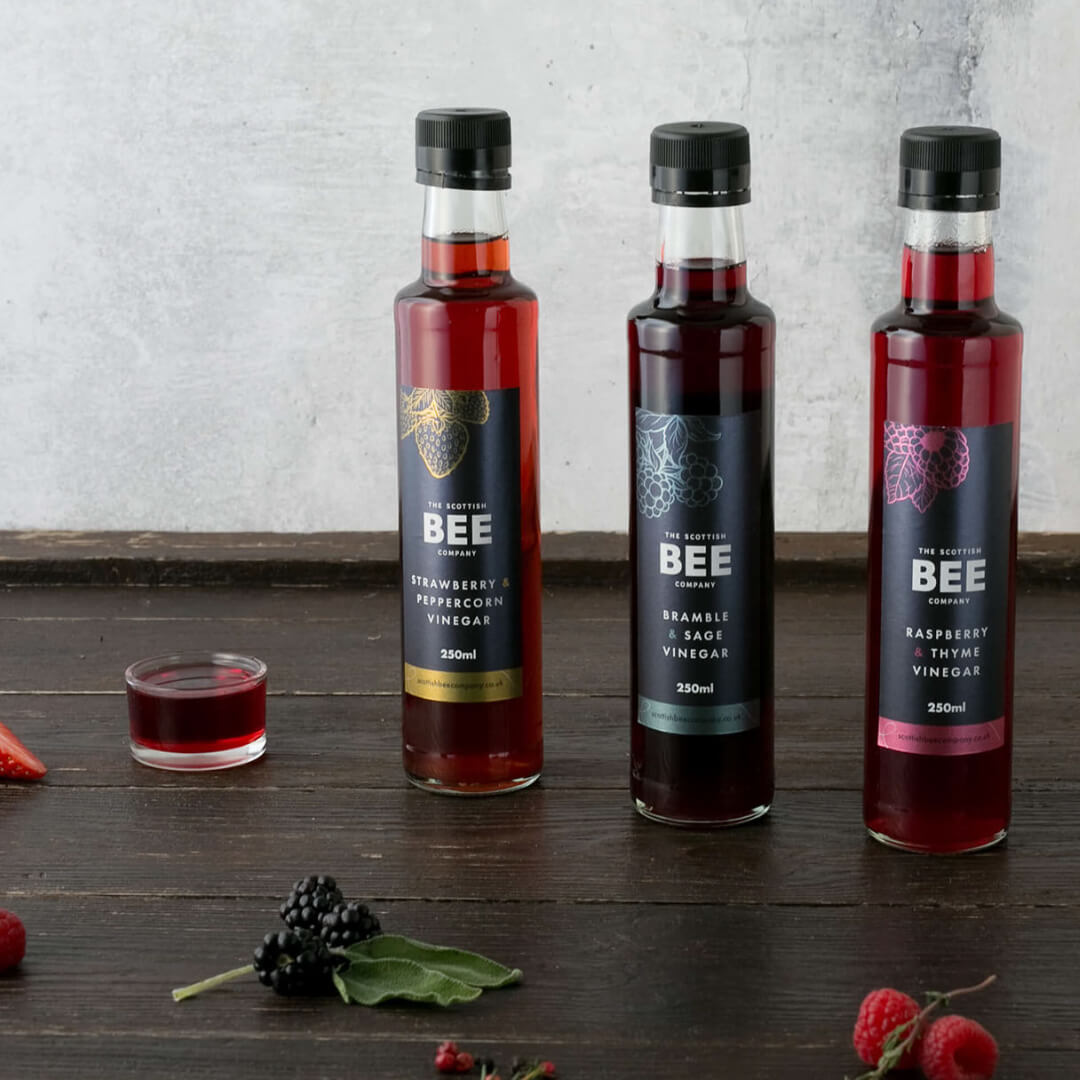 Collection of vinegars on a wooden worktop with fresh berries